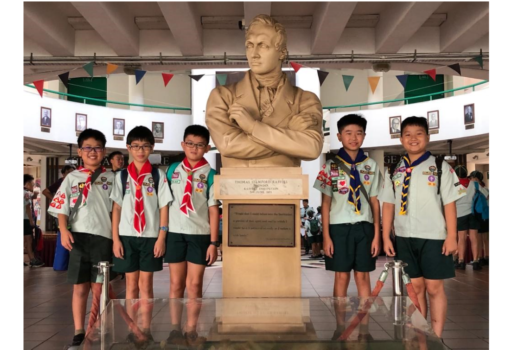A group of primary school boy scouts posing with a statue of the founder of scouts